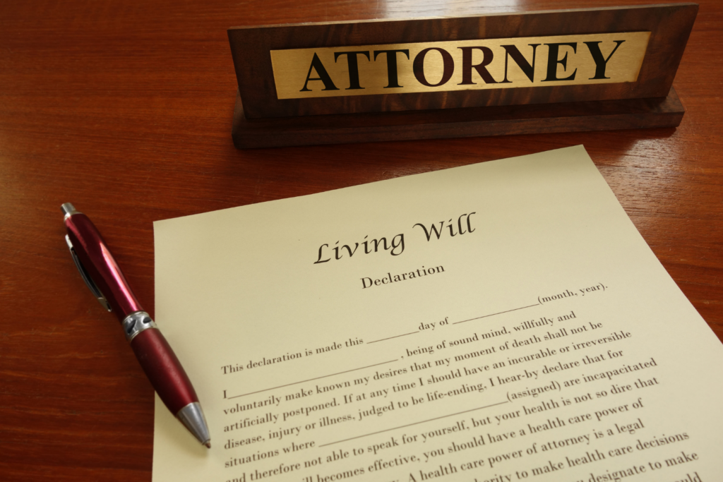Attorney's desk sign with 'ATTORNEY' next to a living will declaration and a red pen on a wooden surface